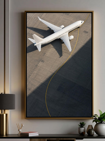 A framed aerial view of a white airplane on an airport tarmac, with a curving yellow line running along the runway.