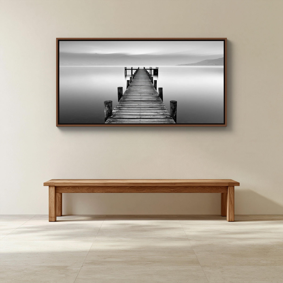 Black and white lake pier canvas wall art, wooden bench sits in front of a framed photograph of a wooden dock leading to a