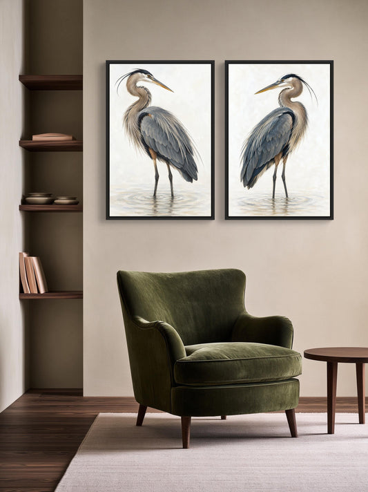 Facing great blue herons canvas wall art, two framed paintings of great blue herons on a wall, with a green armchair in the