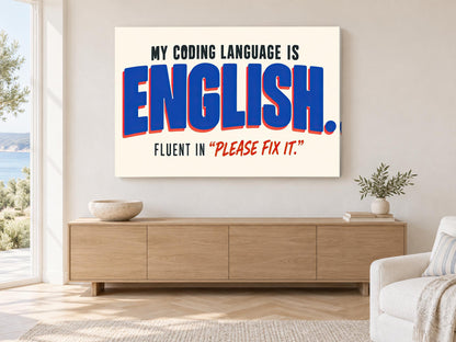 a large poster with the text "MY CODING LANGUAGE IS ENGLISH. FLUENT IN "PLEASE FIX IT"". The poster is displayed on a wall in a room with a wooden cabinet and a potted plant.