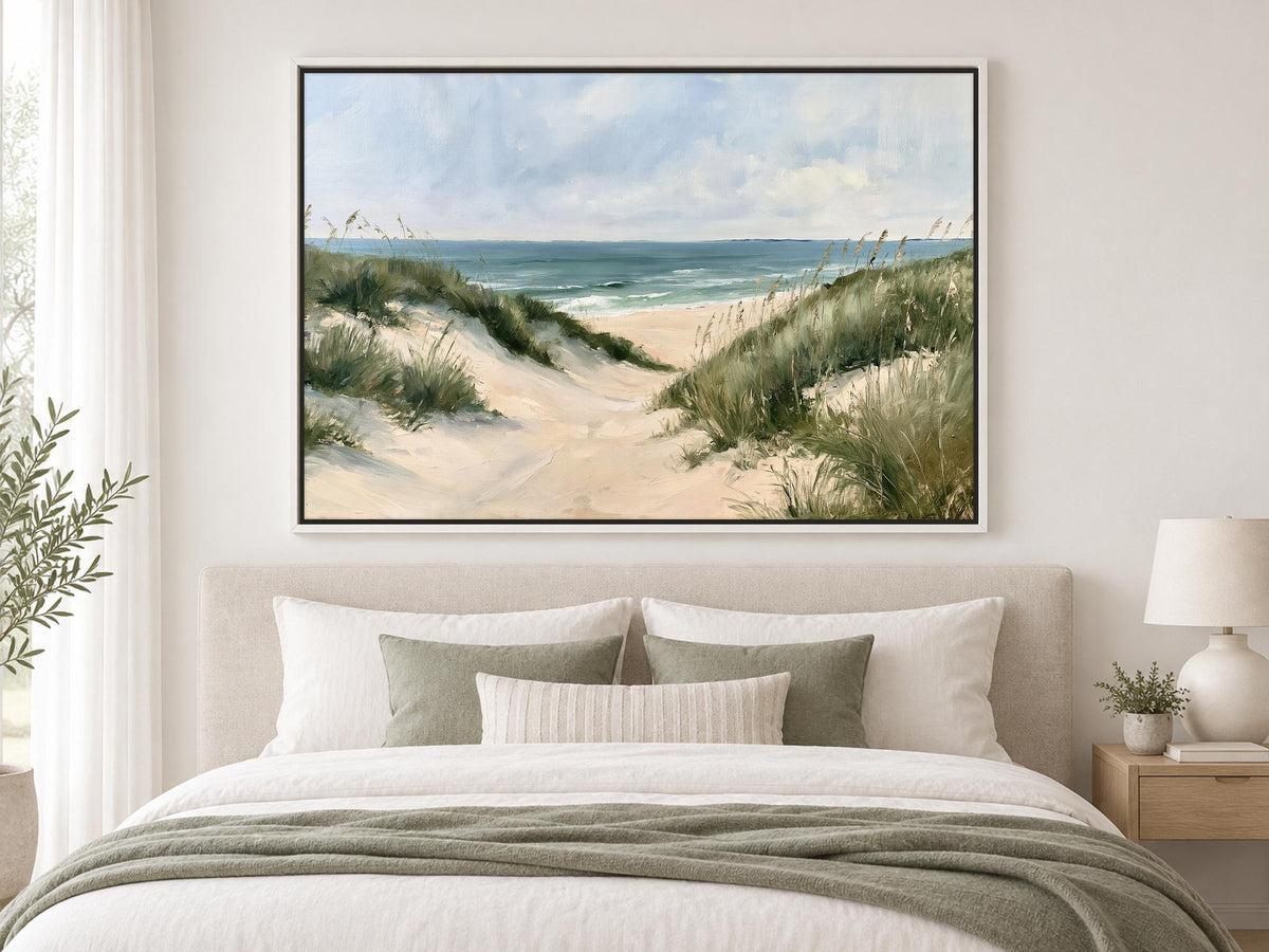 a large painting of a beach scene hanging on a wall above a bed with white bedding and pillows.