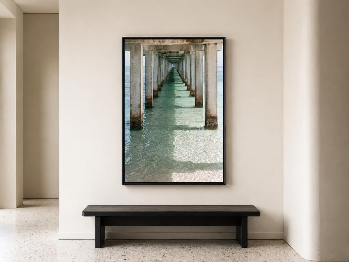 a long, white pier extending into the water, with a black bench positioned in front of it.