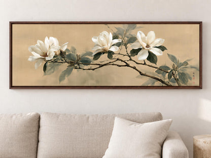 A framed painting of white flowers on a branch hangs on a wall above a beige couch in a living room.