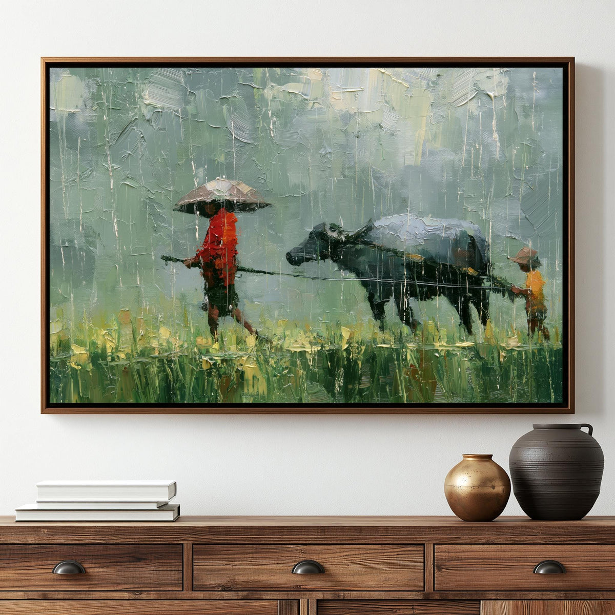 The image is a framed painting depicting a person walking with an umbrella and a cow in a field, with a wooden dresser below it.