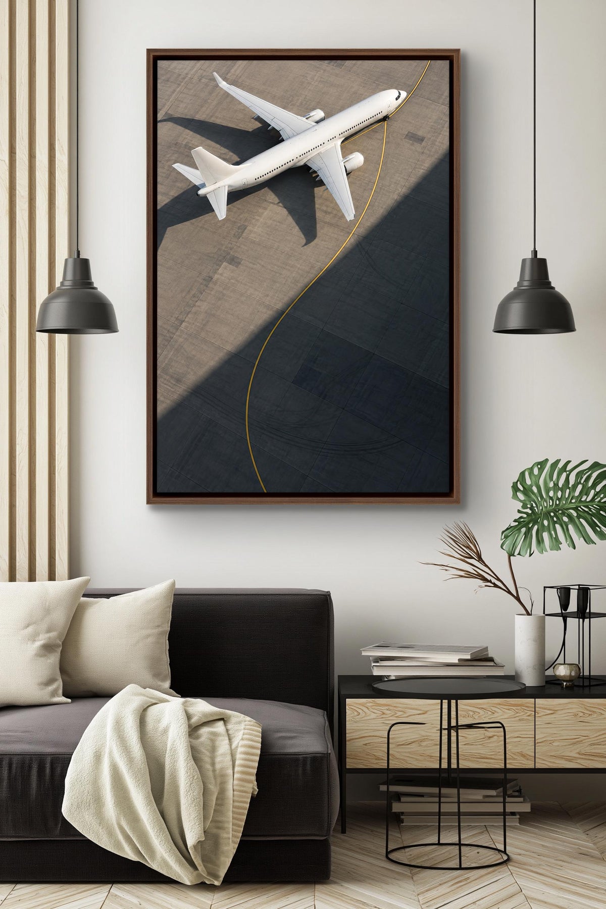 a large framed picture of a white airplane on a dark background, hanging on a wall above a black couch in a modern living room setting.