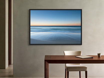 Ocean horizon at dusk canvas wall art, serene beach scene with a wooden table and chair in front of a framed picture of a