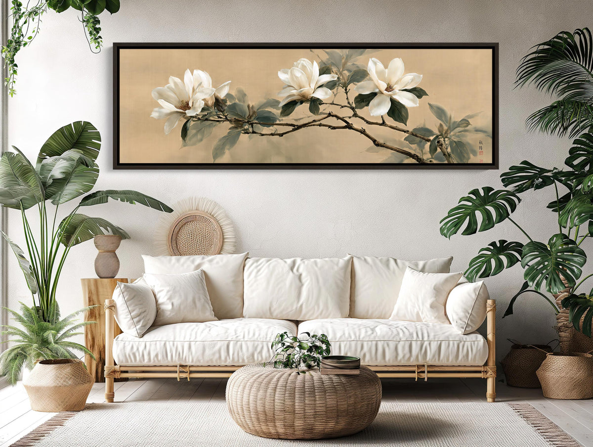 a living room with a large white sofa, a wicker coffee table, and a framed painting of white flowers on the wall above the sofa.