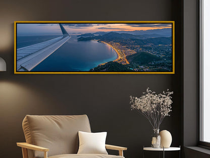 a large, framed aerial view of a coastal city at sunset, with the city's skyline and coastline visible.