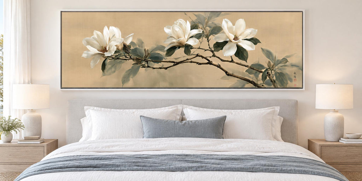 a large, framed painting of white flowers on a wall above a bed with white bedding and pillows.