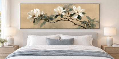 a large, framed painting of white flowers on a wall above a bed with white bedding and pillows.