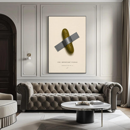 Taped pickle canvas wall art, large framed poster of a pickle taped to a wall, with a tufted gray sofa in the foreground and