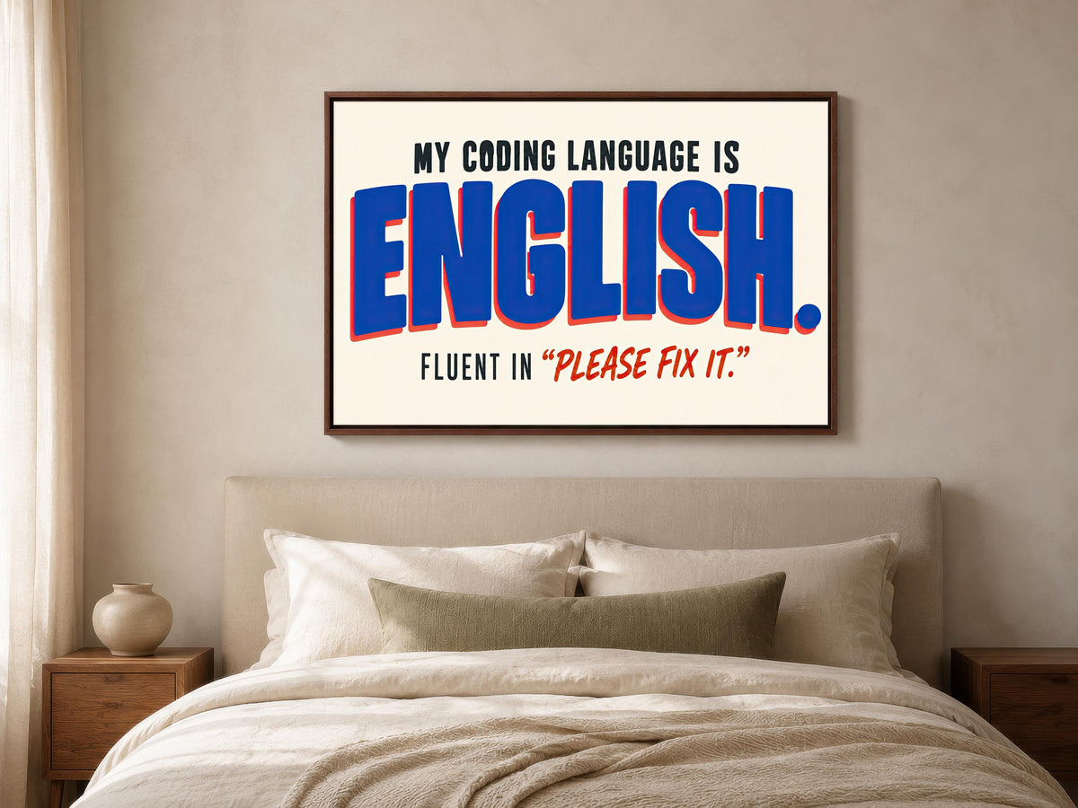 a bedroom with a bed and a framed poster on the wall that reads "MY CODING LANGUAGE IS ENGLISH. FLUENT IN "PLEASE FIX IT"".