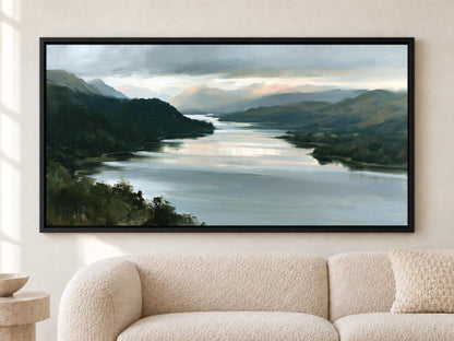 A large framed painting depicting a serene landscape with a river, mountains, and a cloudy sky hangs on a wall above a beige couch.