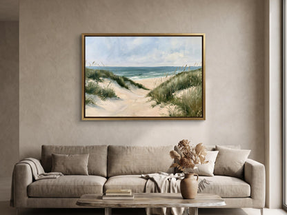 a living room with a large framed painting of a beach scene hanging on the wall above a beige sofa. The painting depicts a sandy beach with a path leading to the ocean, surrounded by grassy dunes. The room has a neutral color scheme, with a wooden coffee table in the center and a vase of flowers on the table.