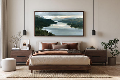 a serene bedroom with a large bed, wooden furniture, and a framed landscape painting hanging above it. The painting features a tranquil scene of a river surrounded by mountains, creating a peaceful and relaxing atmosphere.