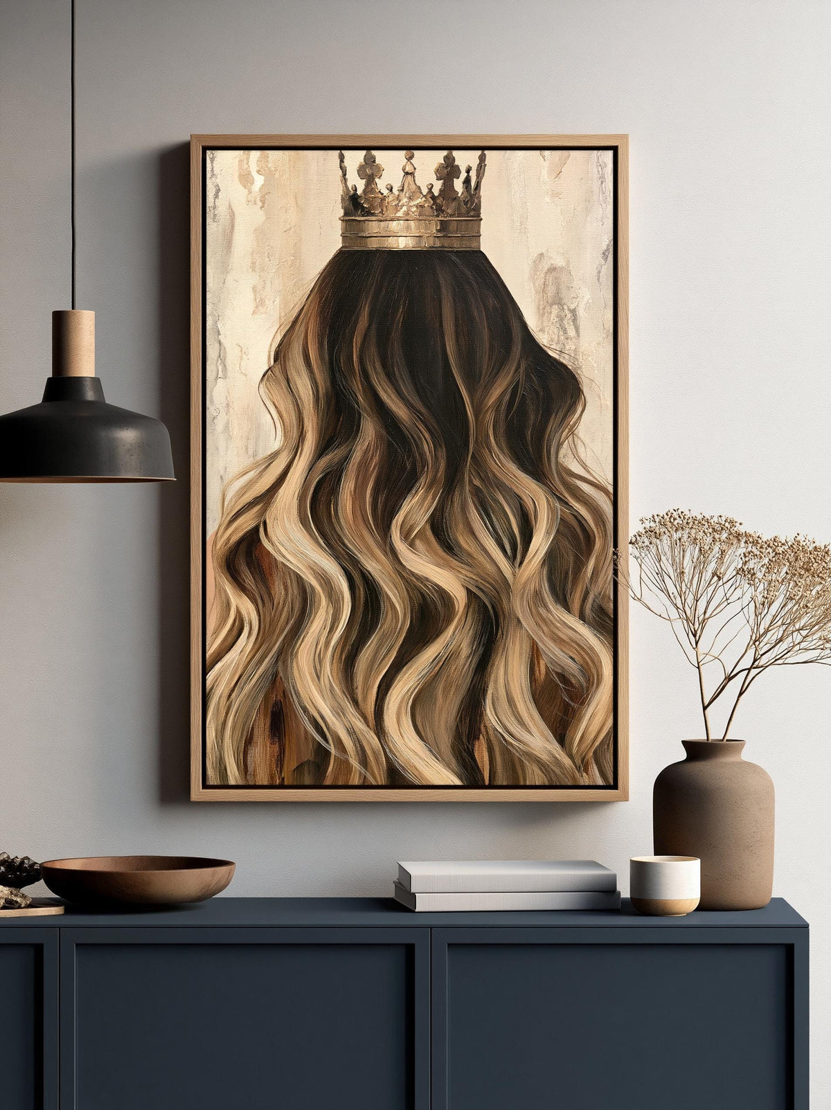 a framed painting of a woman's long, wavy hair with a crown on top, hanging on a wall above a dark blue cabinet.