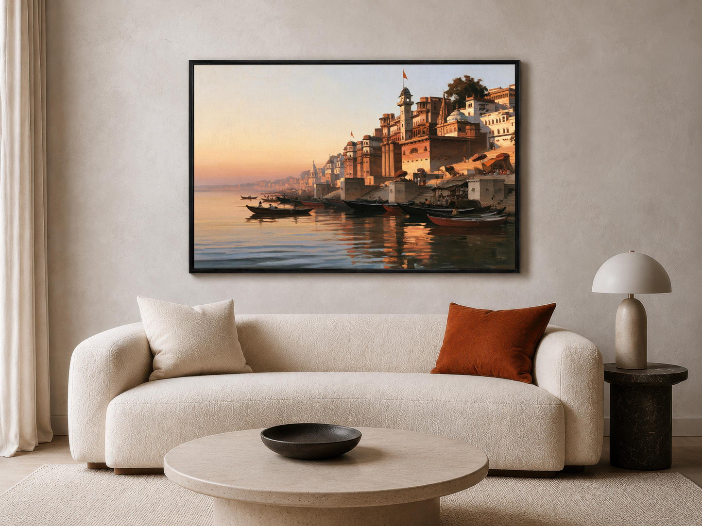 a large, framed painting of a serene waterfront scene with boats and buildings reflected in the water. The painting is hung on a wall above a white sofa with a round coffee table in front of it.