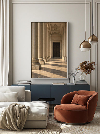 a modern living room with a large framed picture of a hallway with columns hanging on the wall. The room is furnished with a white sofa, a red armchair, and a black side table. The overall design and decor create a stylish and contemporary atmosphere.