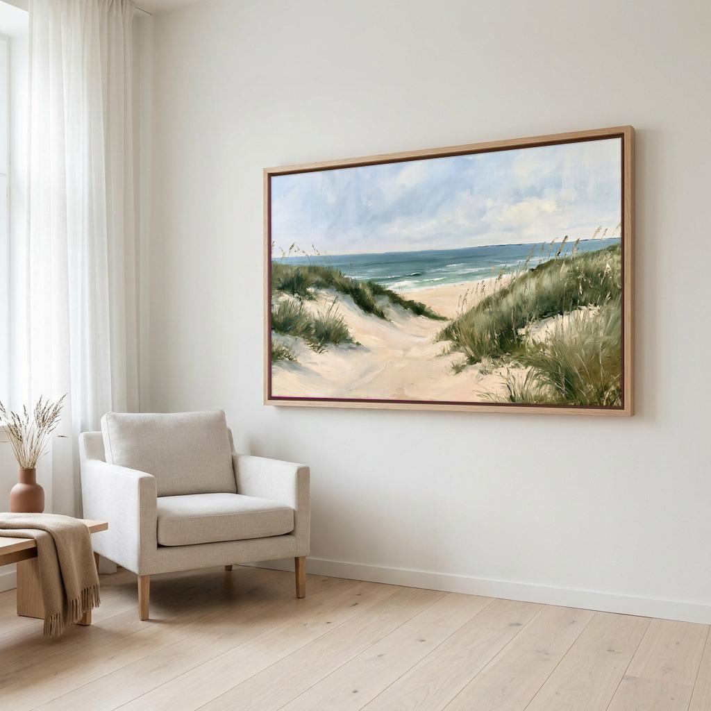 a large painting of a beach scene hanging on a white wall, with a beige armchair positioned in front of it.