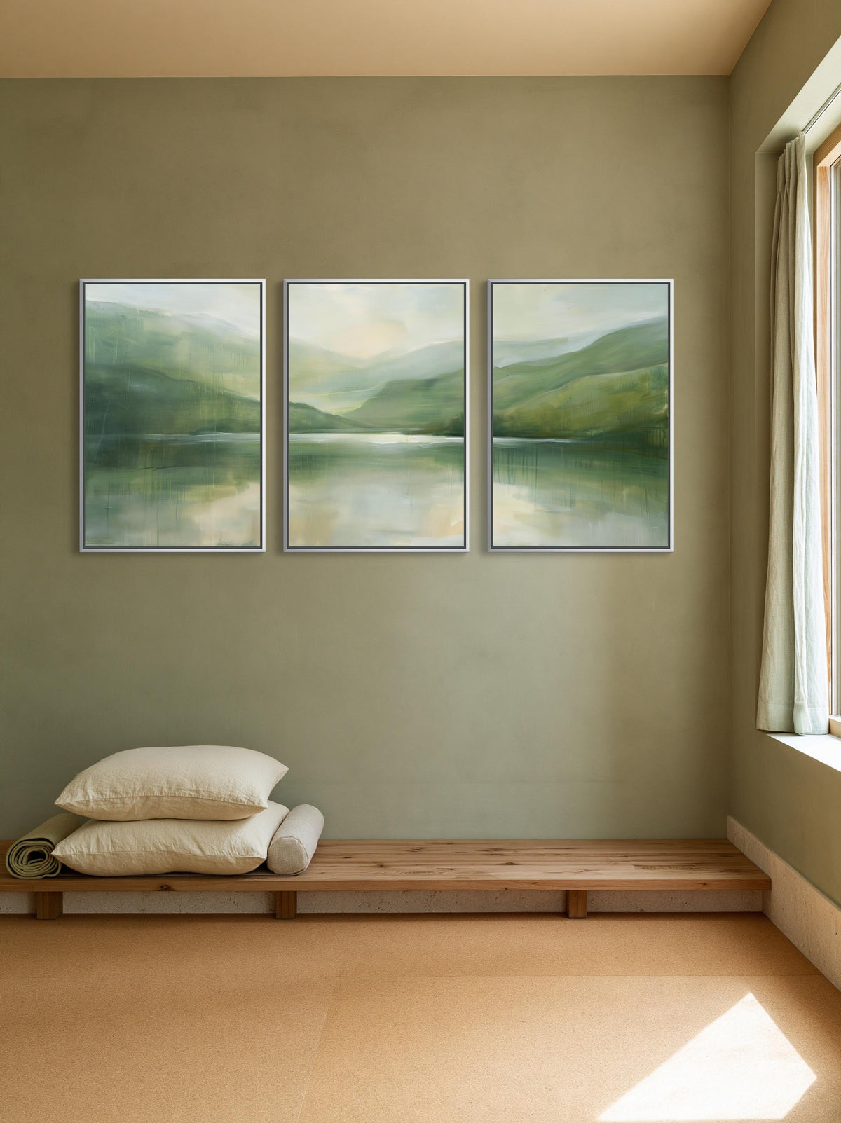 Misty sage lake triptych canvas wall art, serene indoor setting with a wooden bench, a stack of pillows, and three framed