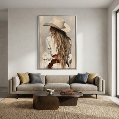 a large framed painting of a woman with long blonde hair wearing a cowboy hat, displayed on the wall above a gray sofa with two throw pillows.