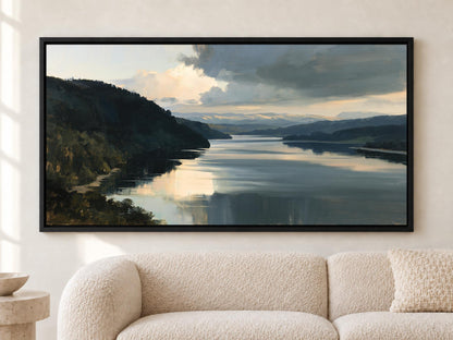 a large, framed painting of a serene landscape depicting a calm lake surrounded by mountains and hills.
