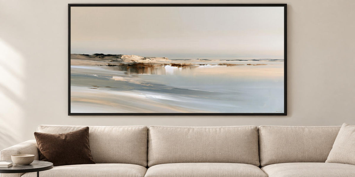 a large, framed painting of a serene landscape depicting a beach with a calm body of water and a rocky shoreline.