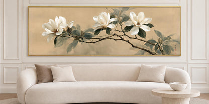 A large painting of white flowers on a branch hangs on a wall above a white sofa with two pillows in a modern living room setting.