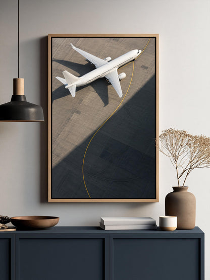 a framed picture of a white airplane on a runway, hanging on a wall above a dark blue cabinet or shelf.