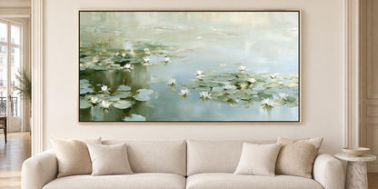 a large painting of water lilies hanging on a wall above a beige sofa in a living room.