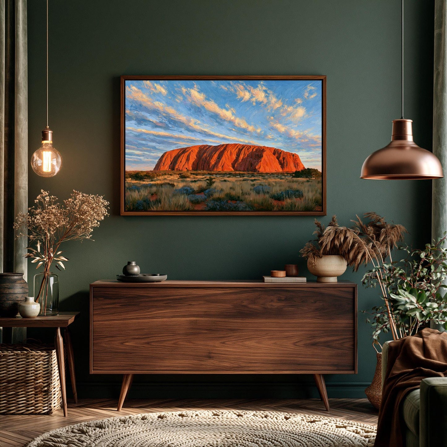 a large wooden dresser with a framed picture of Uluru, a famous red rock formation in Australia, hanging above it. The dresser is situated in a room with a green wall, and there are potted plants and other decorative items on the floor.