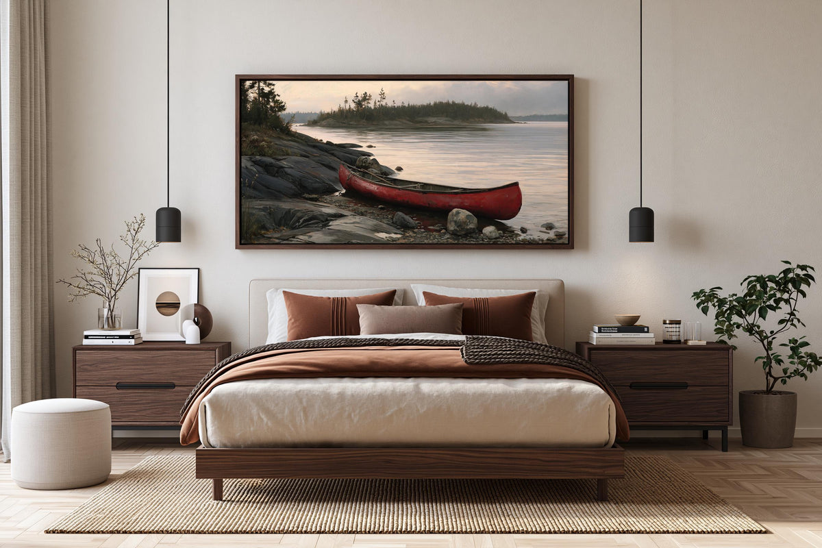 a serene bedroom scene with a large bed, a framed picture of a red canoe on a rocky shore, and a wooden nightstand with a plant on top.