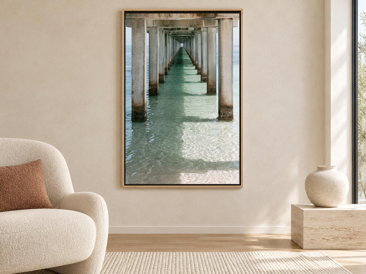 a large framed picture of a long pier extending into the water, with sunlight reflecting on the water's surface.