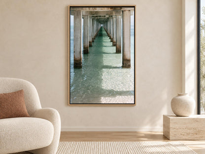 a large framed picture of a long pier extending into the water, with sunlight reflecting on the water's surface.