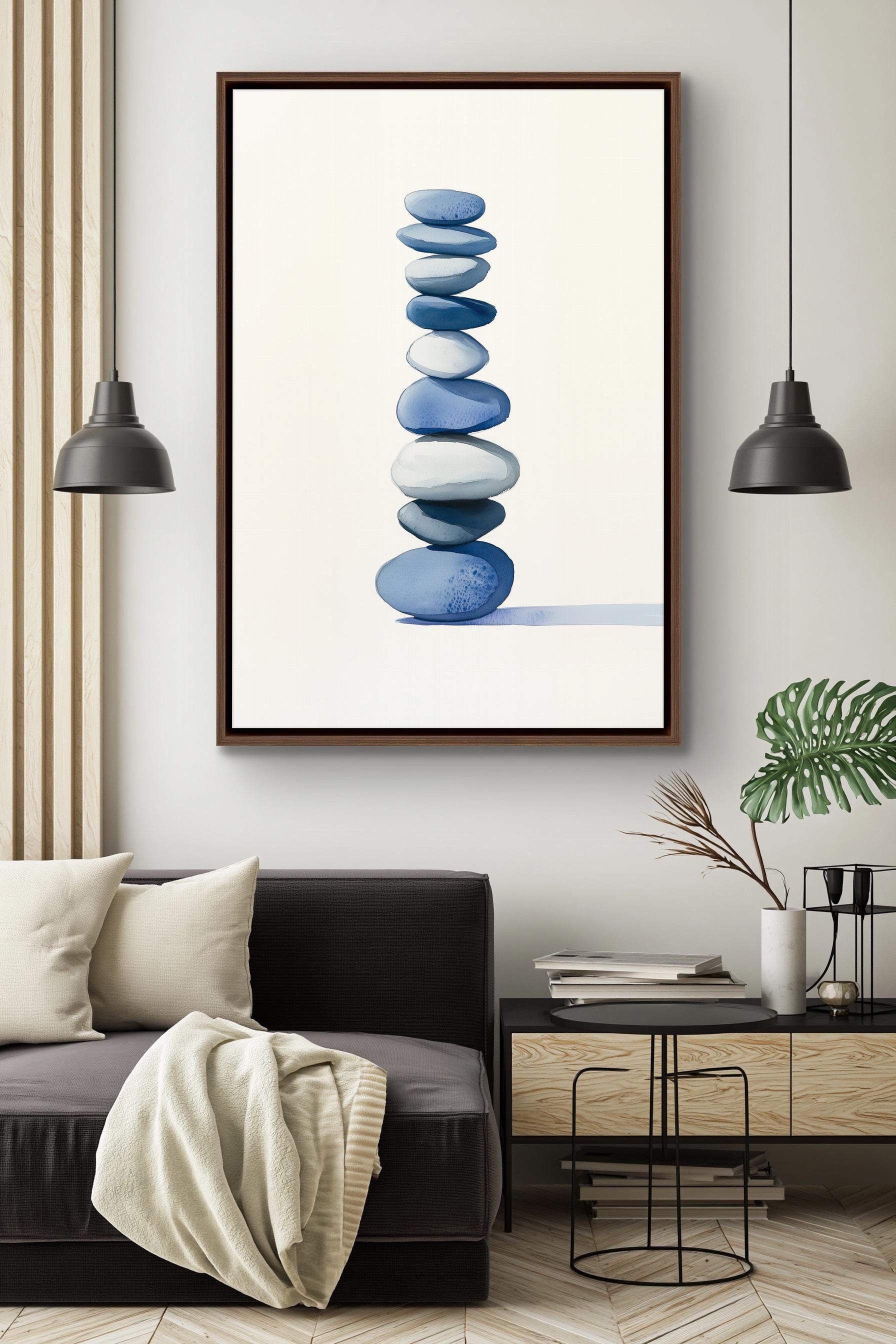 a modern living room with a black sofa, a framed artwork of stacked blue and white stones, and two black pendant lights hanging above the sofa.