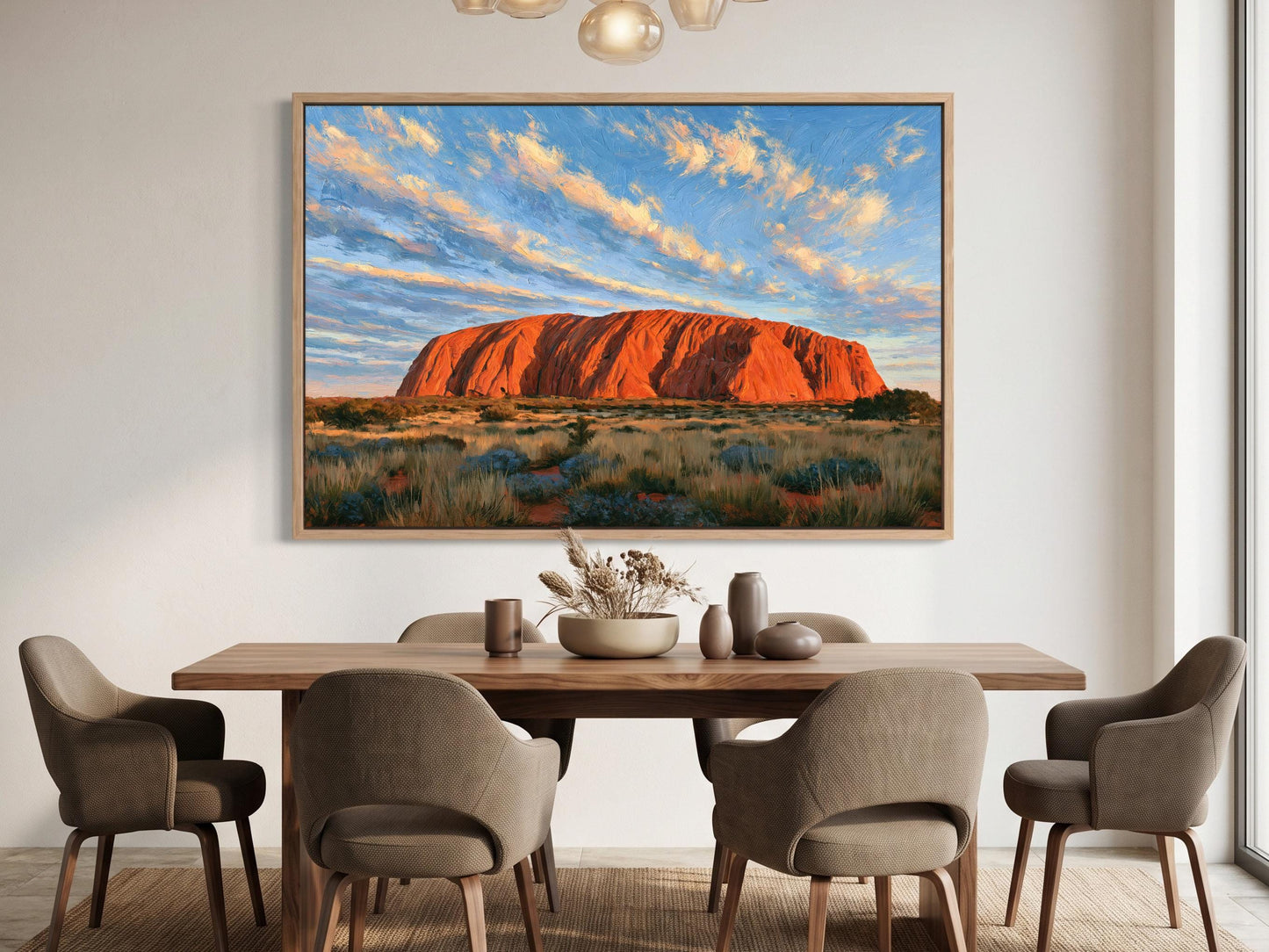 a large painting of Uluru, a famous red rock formation in Australia, hanging on the wall above a wooden dining table with six chairs.