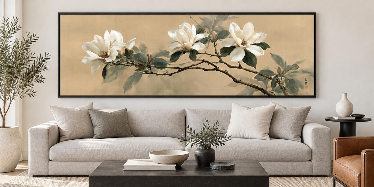 a large painting of white flowers on a branch hanging on a wall above a gray sofa in a living room.