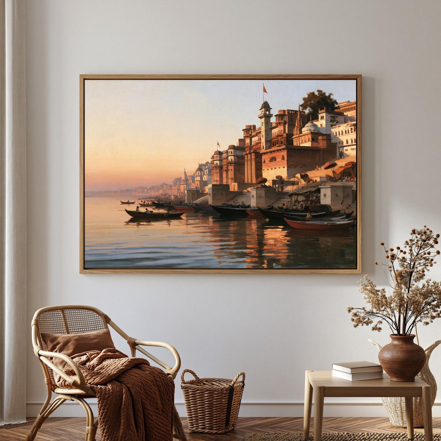 a large painting of a cityscape with boats on the water, hanging on a wall in a room with a wicker chair, a small table with a vase of flowers, and a bookshelf.
