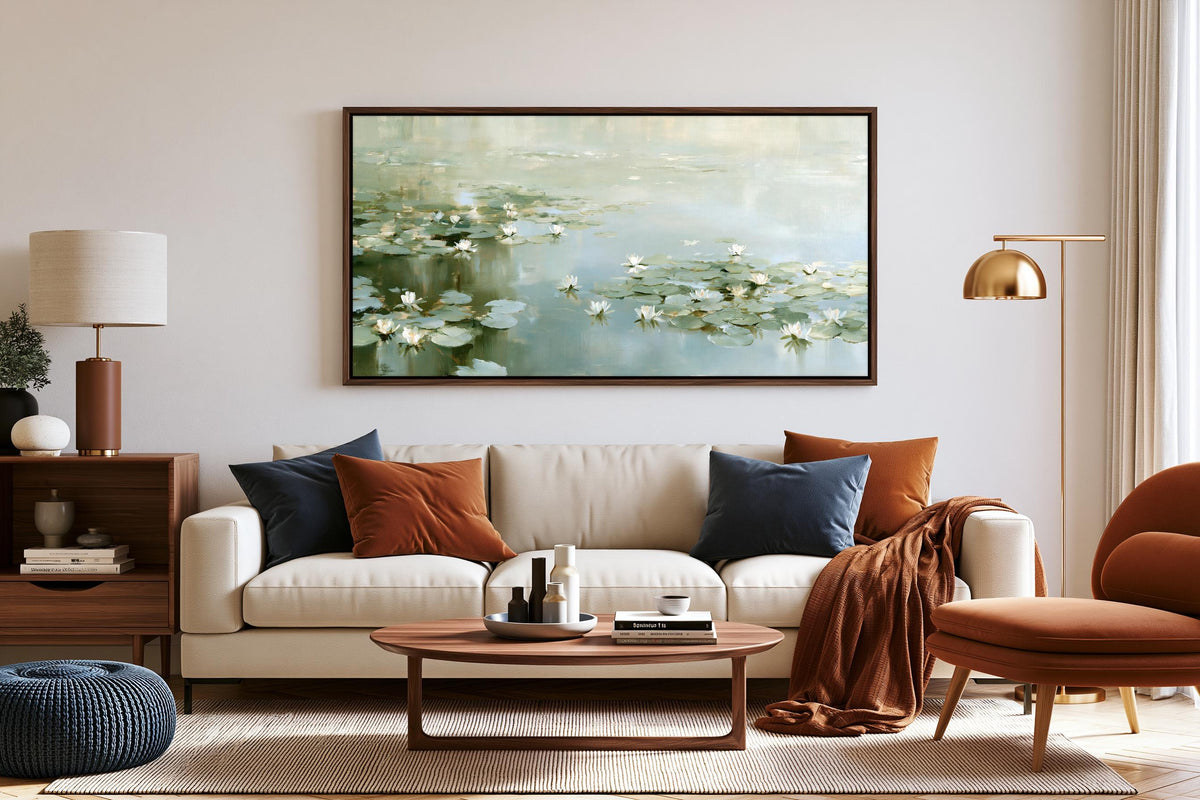 a cozy living room with a large painting of water lilies hanging on the wall above a white sofa. The room is furnished with a wooden coffee table, a red armchair, and a wooden side table with a lamp. The overall decor has a warm and inviting atmosphere.