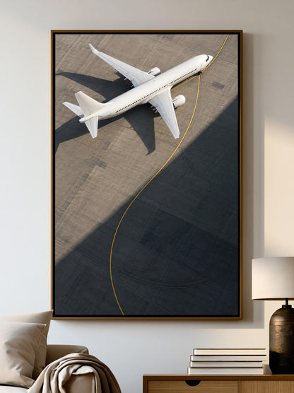 A large framed picture of a white airplane on an airport tarmac is displayed on the wall in a living room setting.