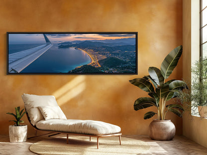 a large, framed aerial view of a coastal city at sunset, with the city's skyline and beach visible.