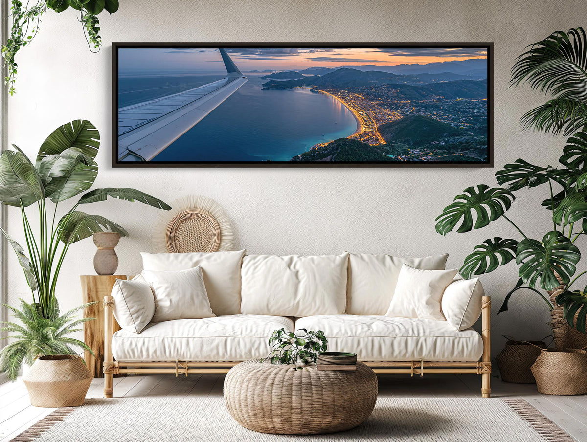 a large, framed picture of an airplane wing with a stunning aerial view of a coastal city at sunset.