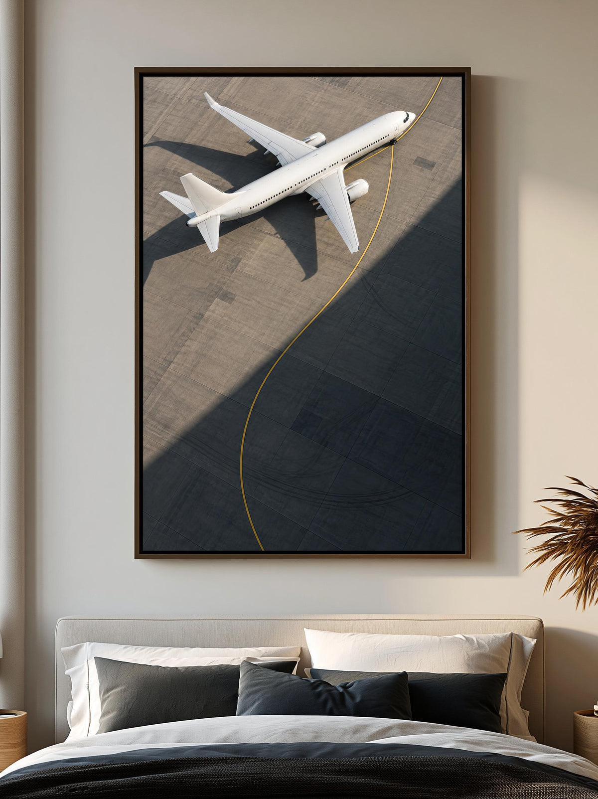 a large framed picture of a white airplane on a runway, hanging on a wall above a bed with white pillows and a black comforter.