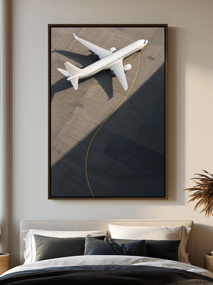 a large framed picture of a white airplane on a runway, hanging on a wall above a bed with white pillows and a black comforter.