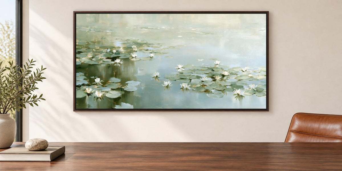 a large framed painting of a serene pond with lily pads hanging on a wall above a wooden table.
