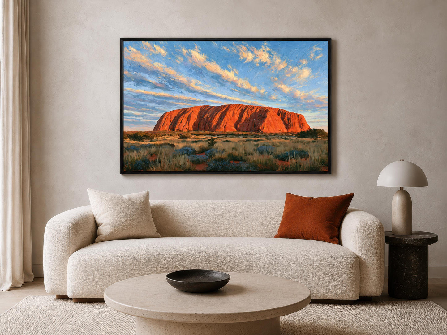 a large, framed painting of Uluru, a famous red rock formation in Australia, hanging on the wall of a living room.