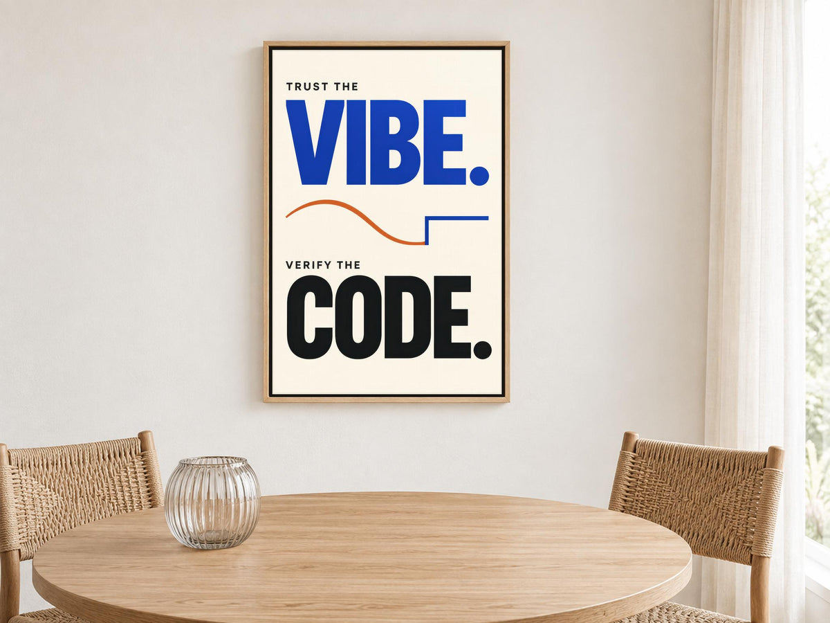 a framed poster with the text "Trust the VIBE. Verify the CODE." displayed on a wall above a wooden table with two chairs.