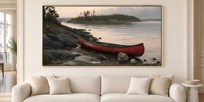 A large framed painting depicting a red canoe resting on a rocky shore, with a calm lake and trees in the background.