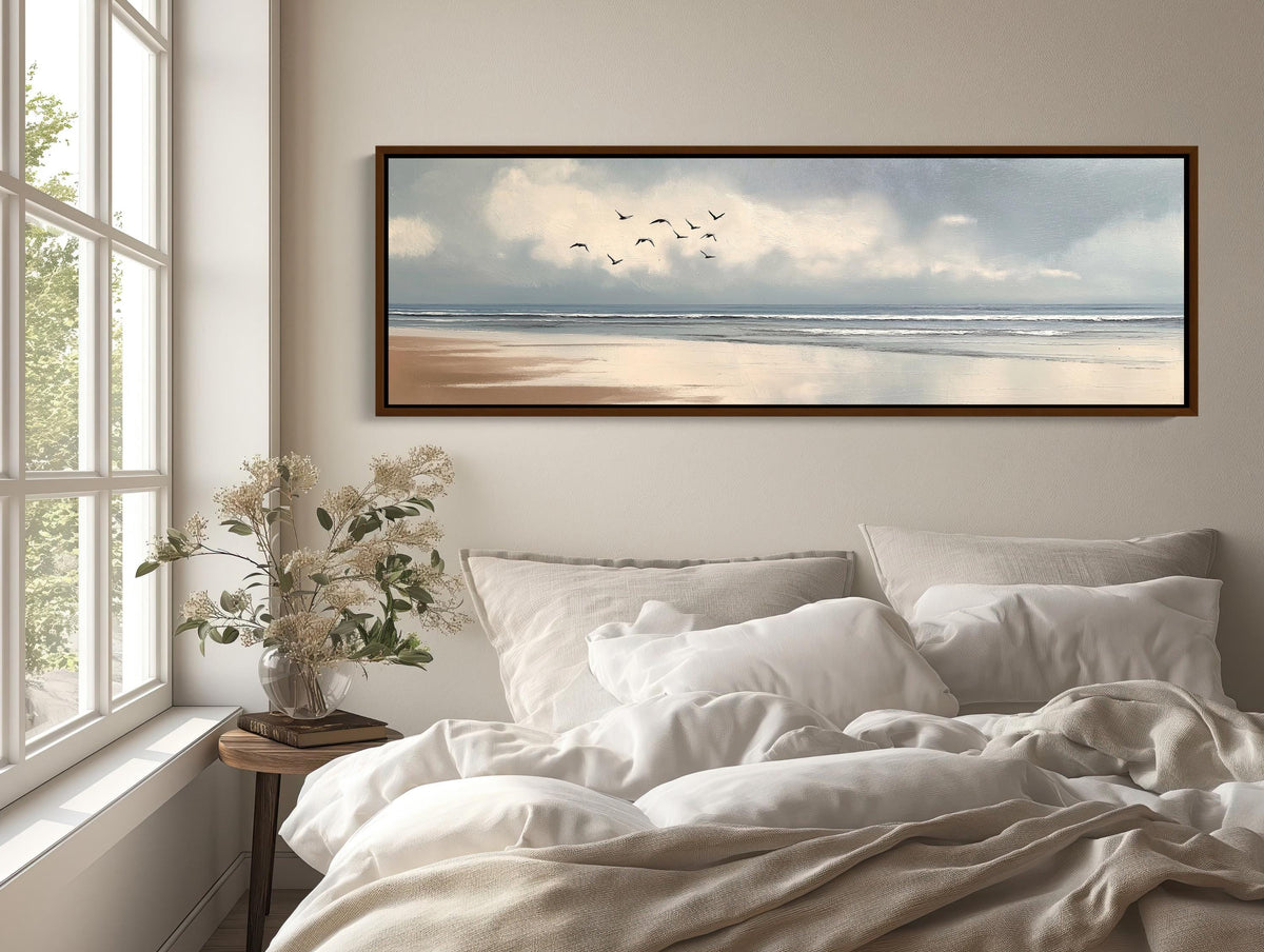 Birds over calm beach canvas wall art, bed with a white comforter and a painting on the wall