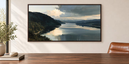 a large painting of a serene landscape with a calm lake and mountains in the background, hanging on a wall above a wooden table.